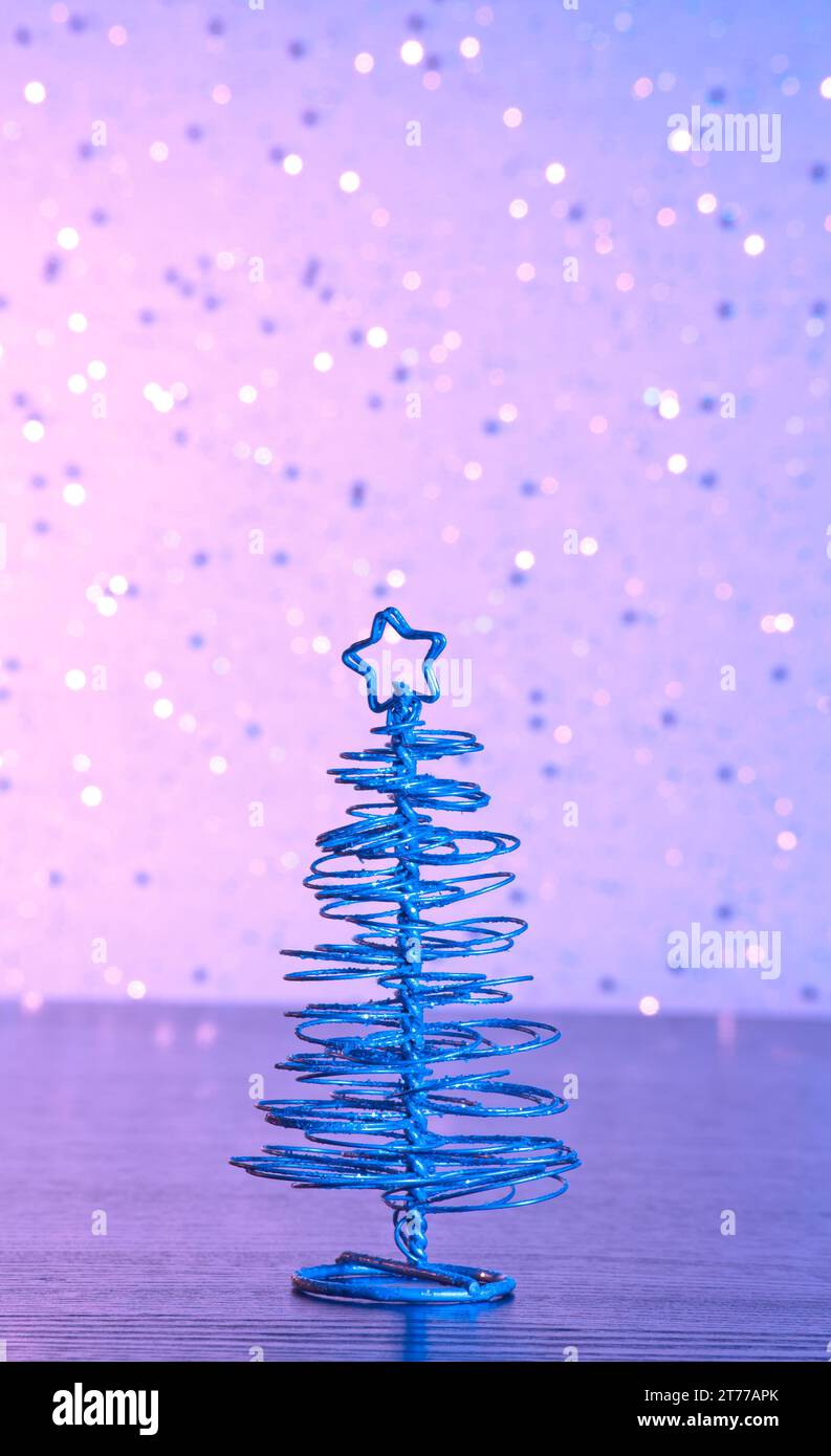 blue metallic modern christmas tree on wood table on blue and violet tint light bokeh background Stock Photo