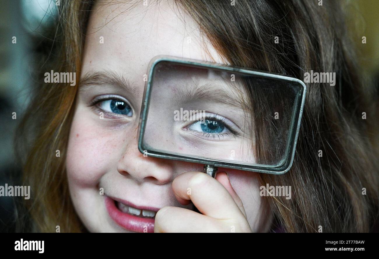 Young girl of 6 years ole playing with a magnifying glass Stock Photo