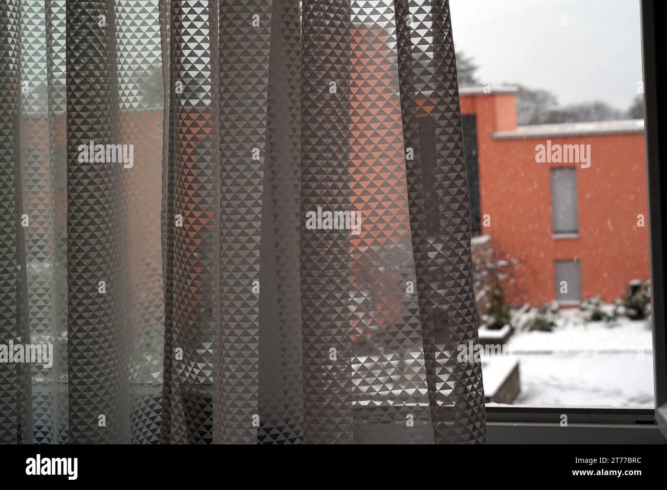 Yard in winter under snow captured from an open window with a curtain slightly blowing in the wind. Stock Photo