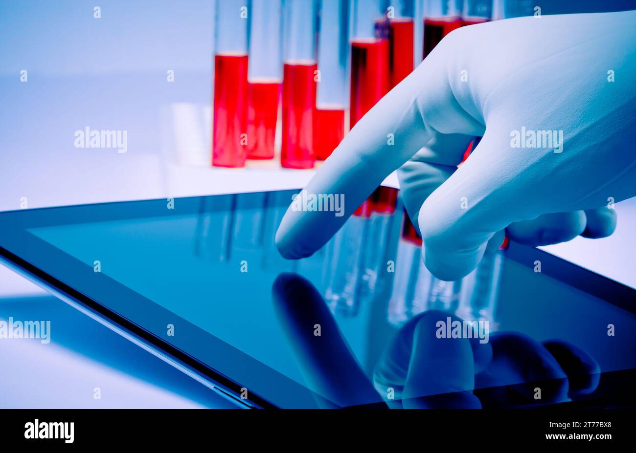 hand in medical blue glove touching modern digital tablet in laboratory. Concept of medical or research theme Stock Photo