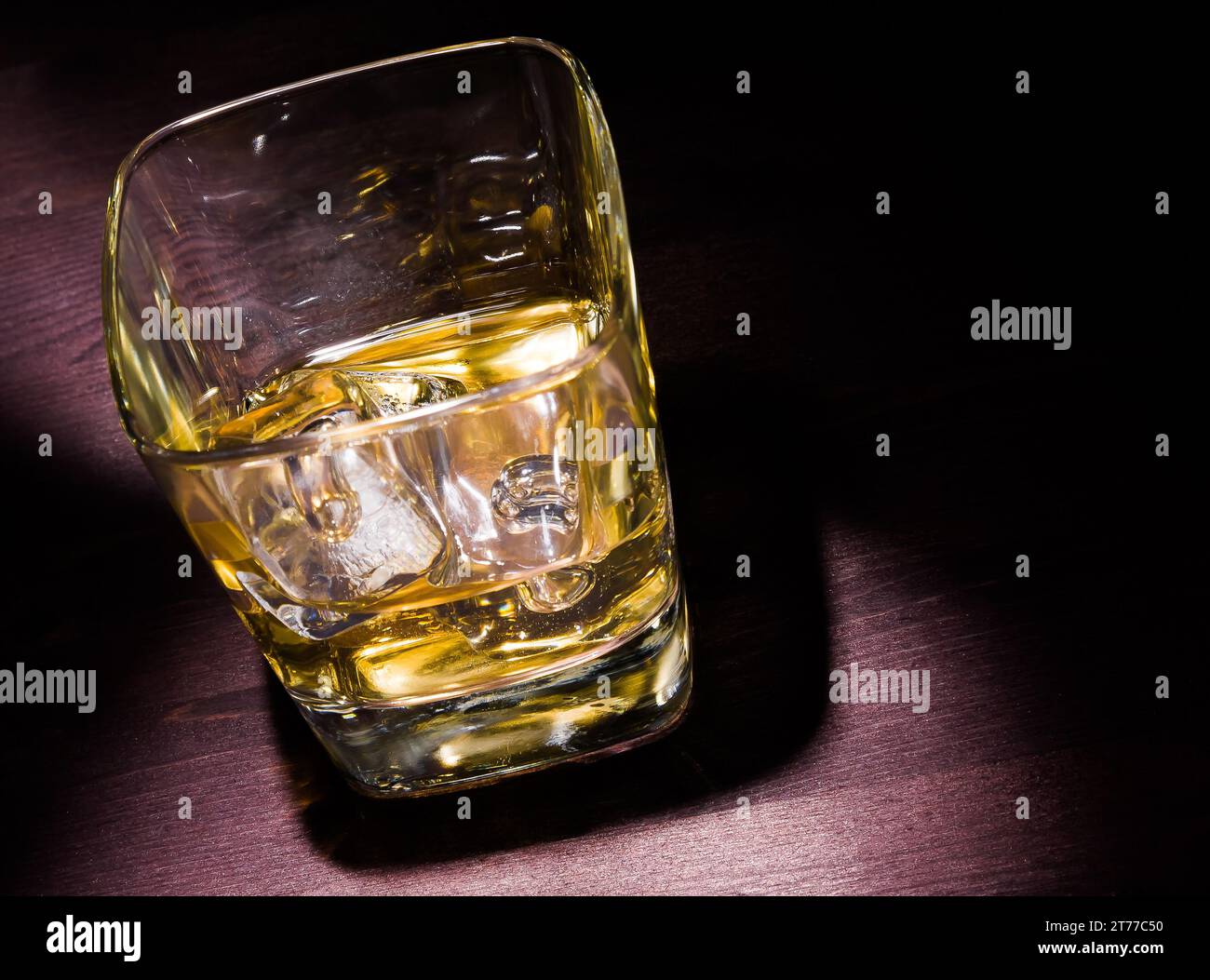 drink series, one glass of whiskey with ice on old wood table and hard light,  pub atmosphere with space for text Stock Photo