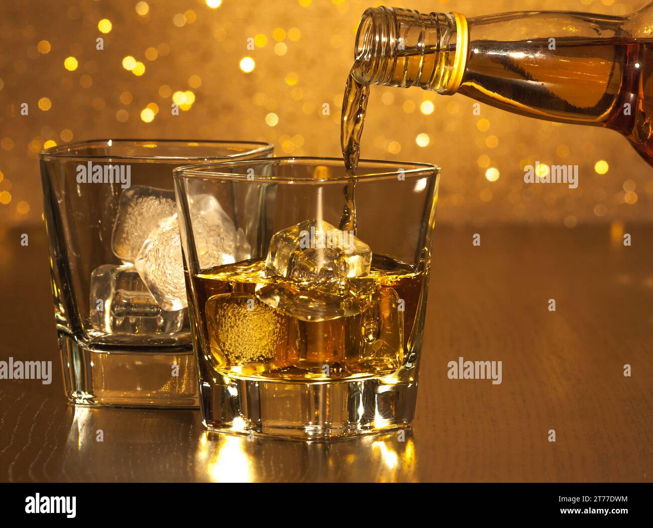 barman pouring whiskey in front of empty whiskey glass on gold bokeh Stock Photo