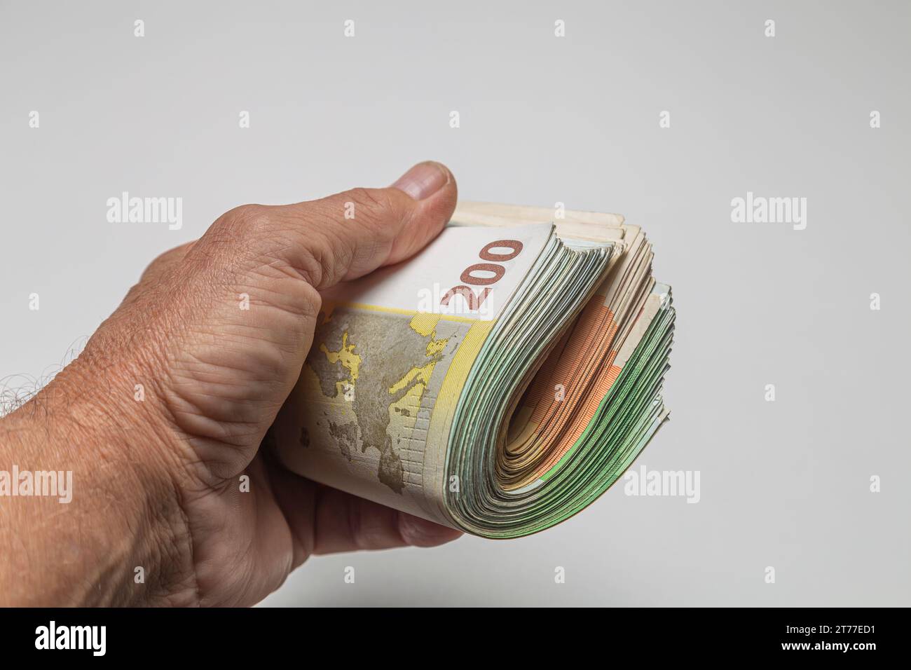 Man's hand holding a bundle of euro banknotes on white background Stock ...