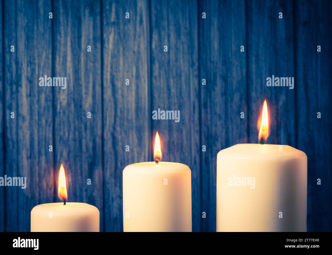 three white candles on warm atmosphere and old wooden background Stock Photo
