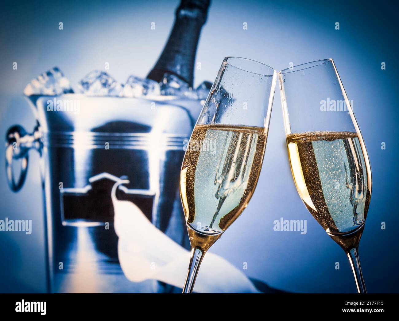 champagne flutes with golden bubbles make cheers in front of champagne bottle in bucket background Stock Photo