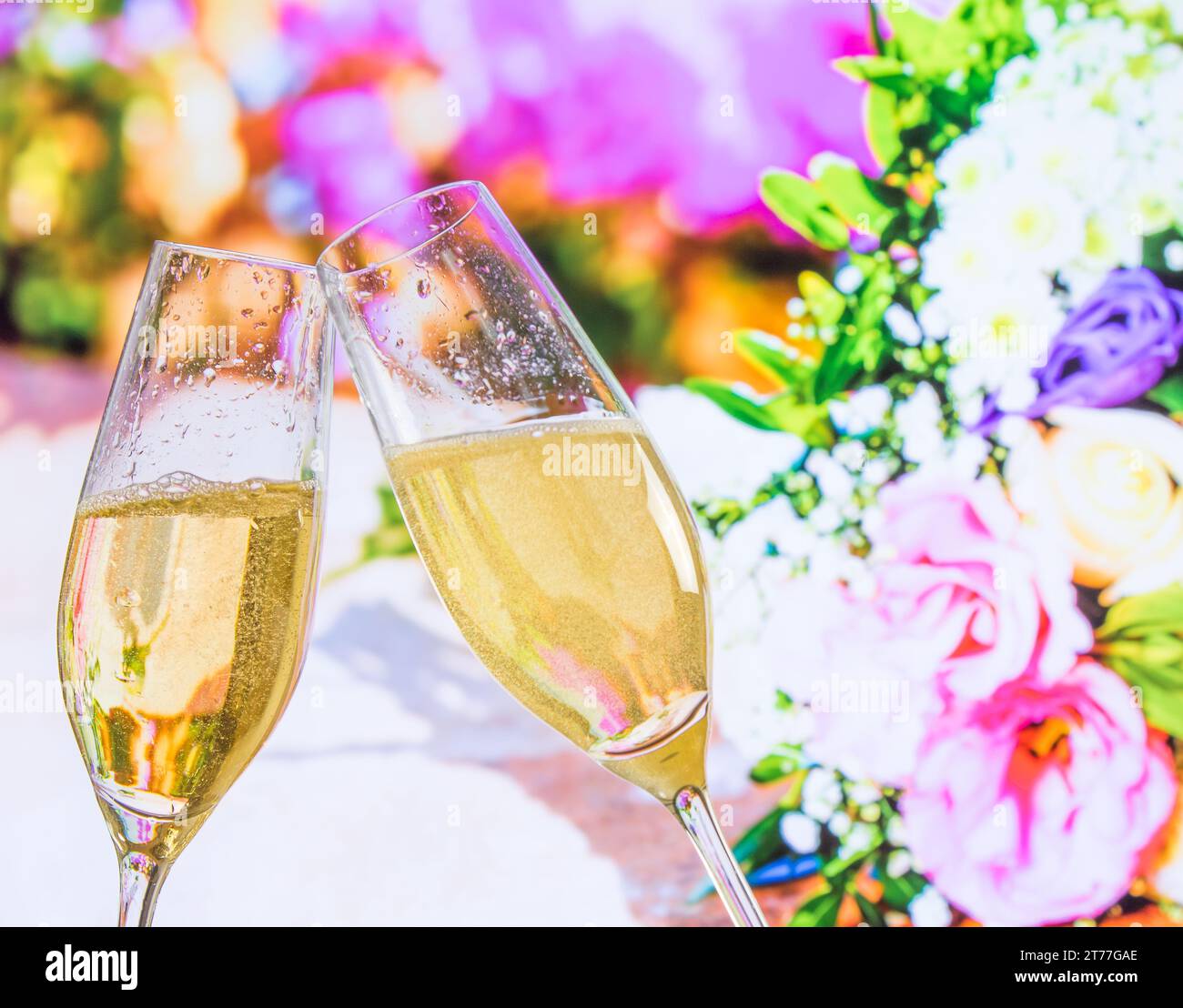 champagne flutes with golden bubbles make cheers on wedding flowers background Stock Photo