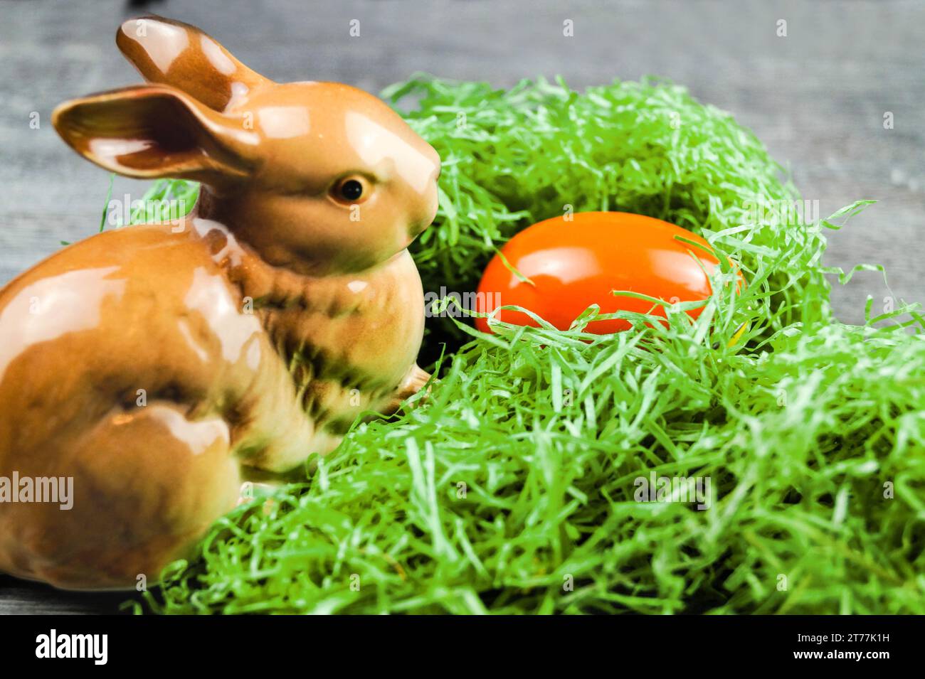 bunny figure with Easter egg in Easter nest on gray Stock Photo