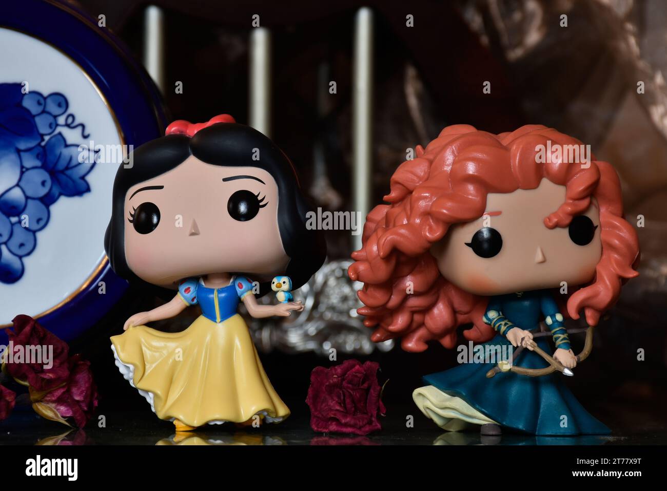 Funko Pop action figures of Disney princesses Snow White and Merida (Brave). Medieval castle, fabulous kingdom, red roses, porcelain blue keg. Stock Photo