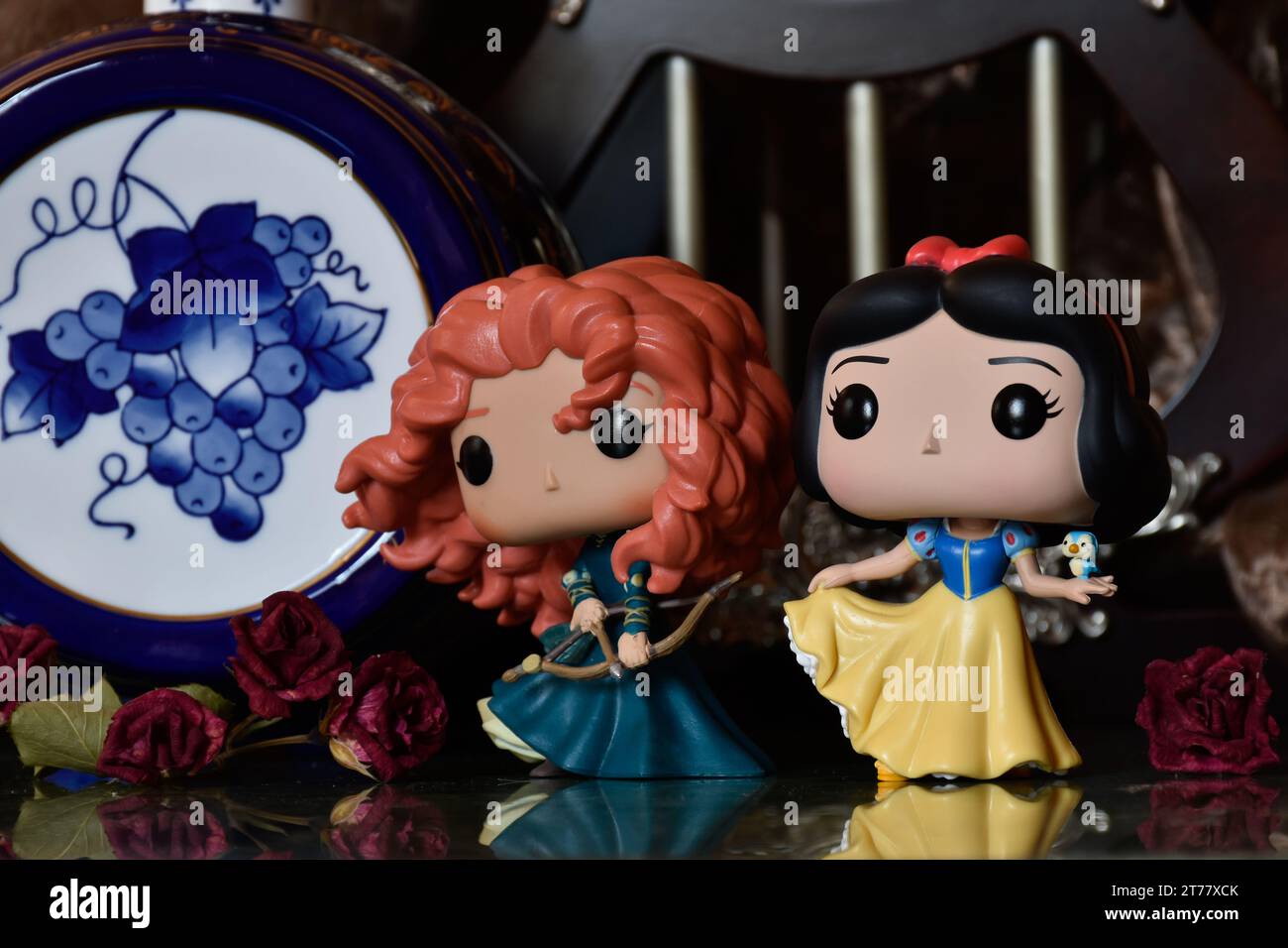 Funko Pop action figures of Disney princesses Merida (Brave) and Snow White. Medieval castle, fabulous kingdom, red roses, porcelain blue keg. Stock Photo