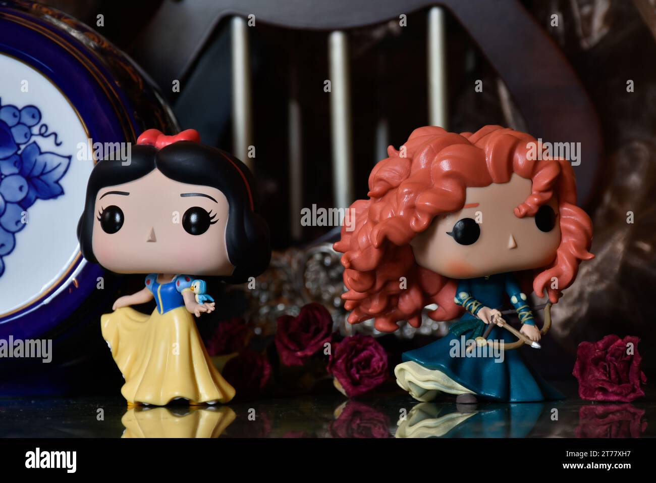 Funko Pop action figures of Disney princesses Snow White and Merida (Brave). Medieval castle, fabulous kingdom, red roses, porcelain blue keg. Stock Photo