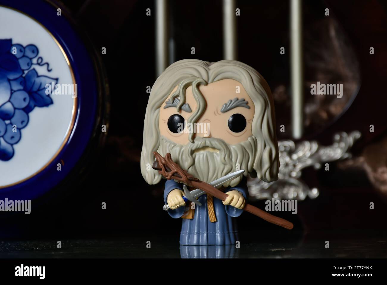 Funko Pop action figure of wizard Gandalf the Grey from fantasy movie The Lord of the Rings. Dark ancient palace with columns, porcelain blue keg. Stock Photo