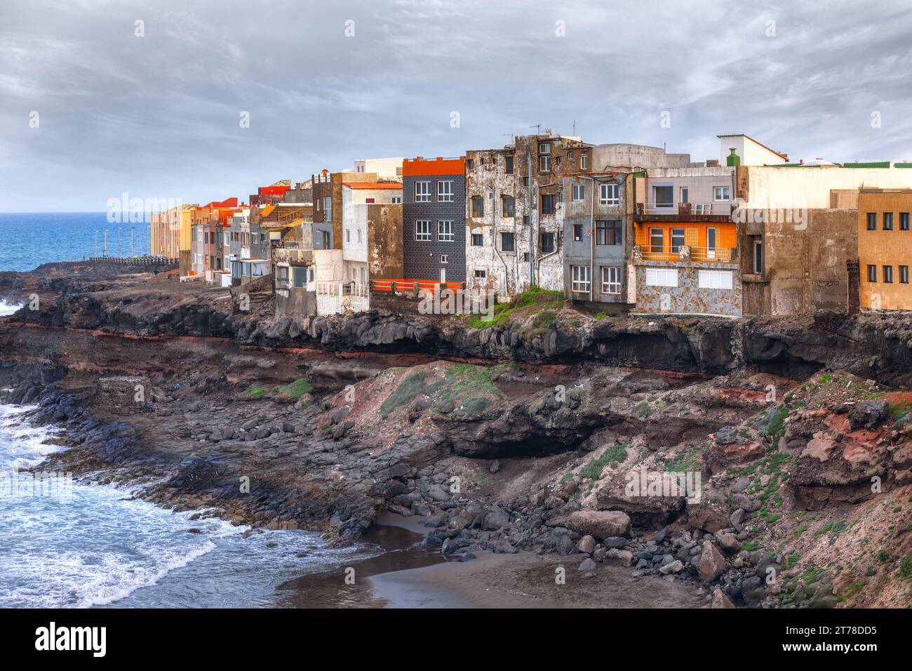A row of houses is perched along the edge of an ocean landslide coast . Colorful houses on the coast of Gran Canaria, Canary Islands, Spain Stock Photo