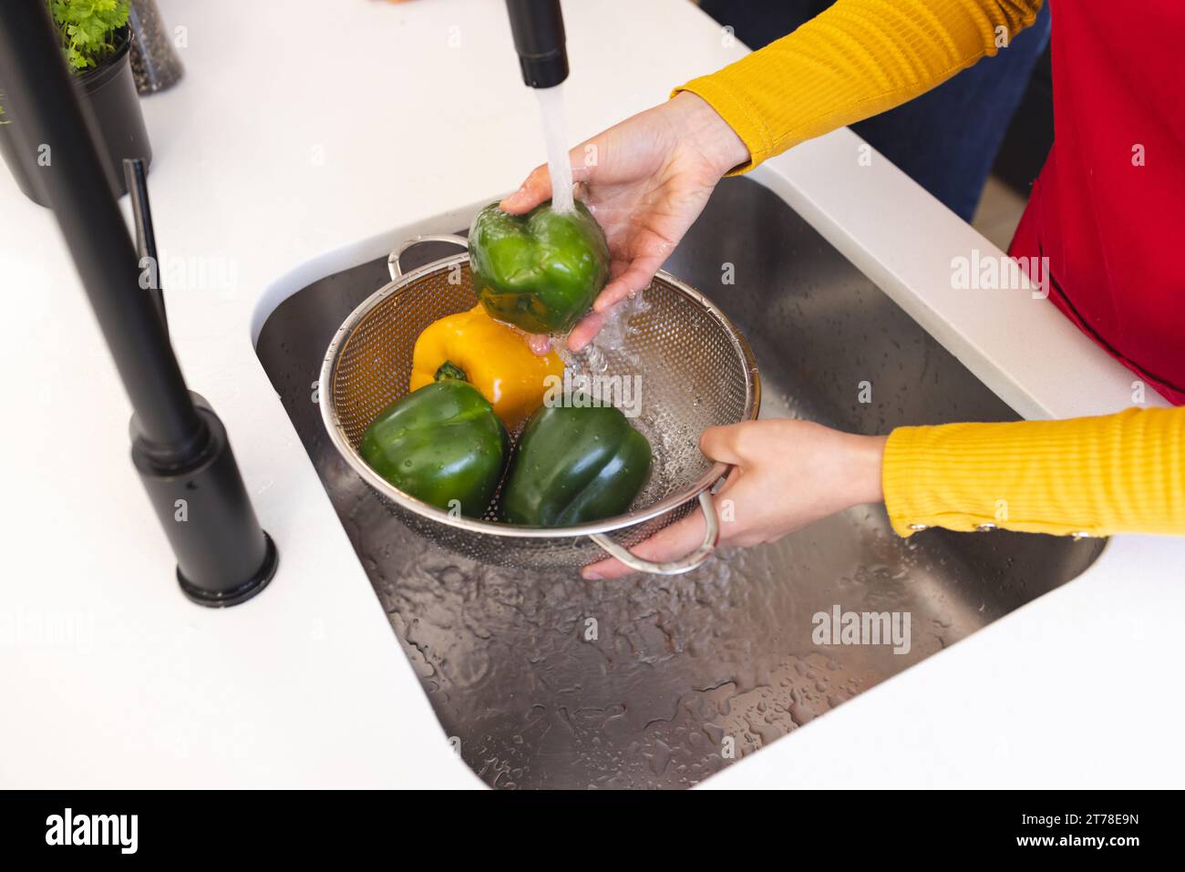 Midsection of biracial woman washing vegetables in kitchen sink at home Stock Photo