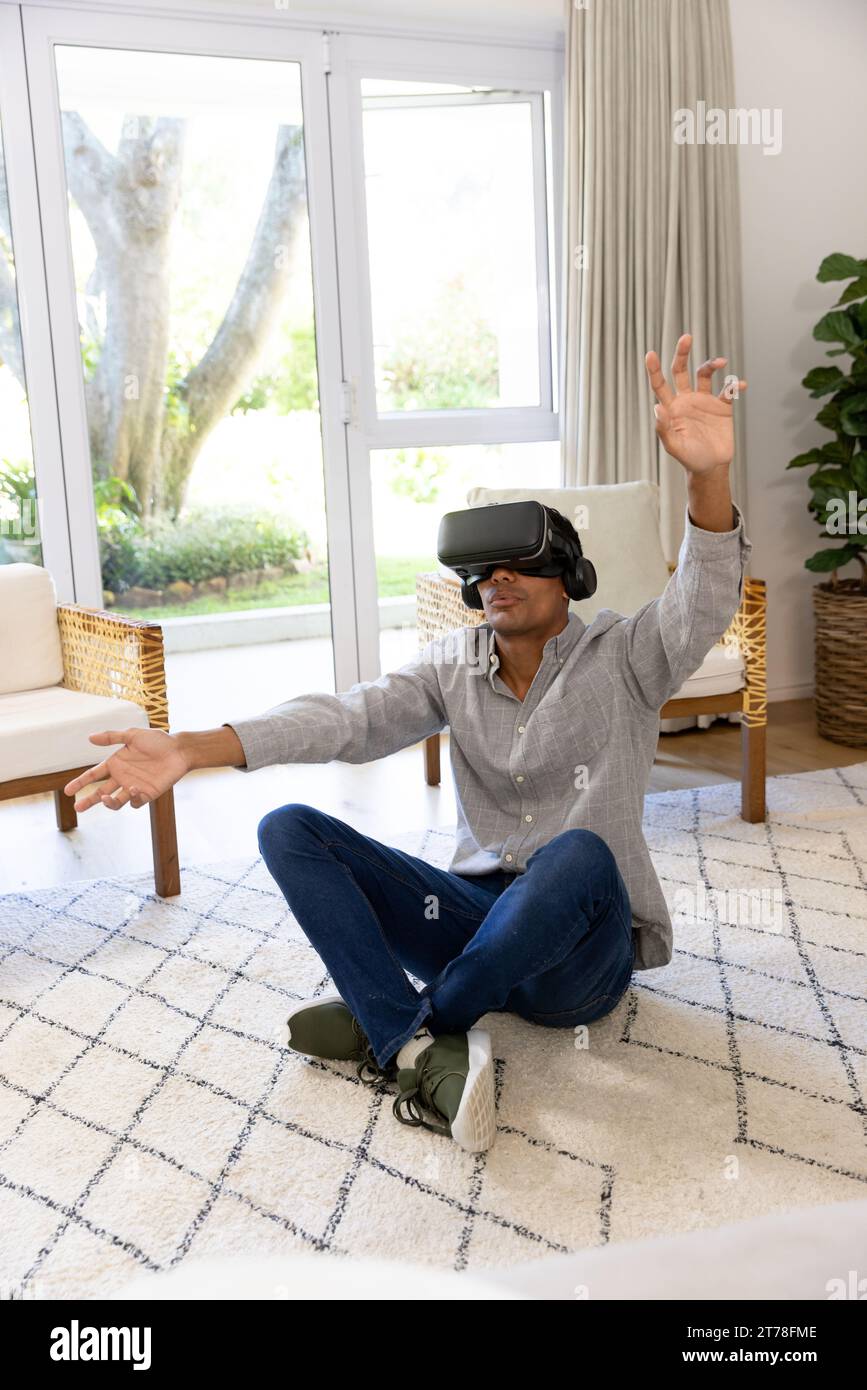 Biracial man using vr headset touching virtual screen at home Stock Photo