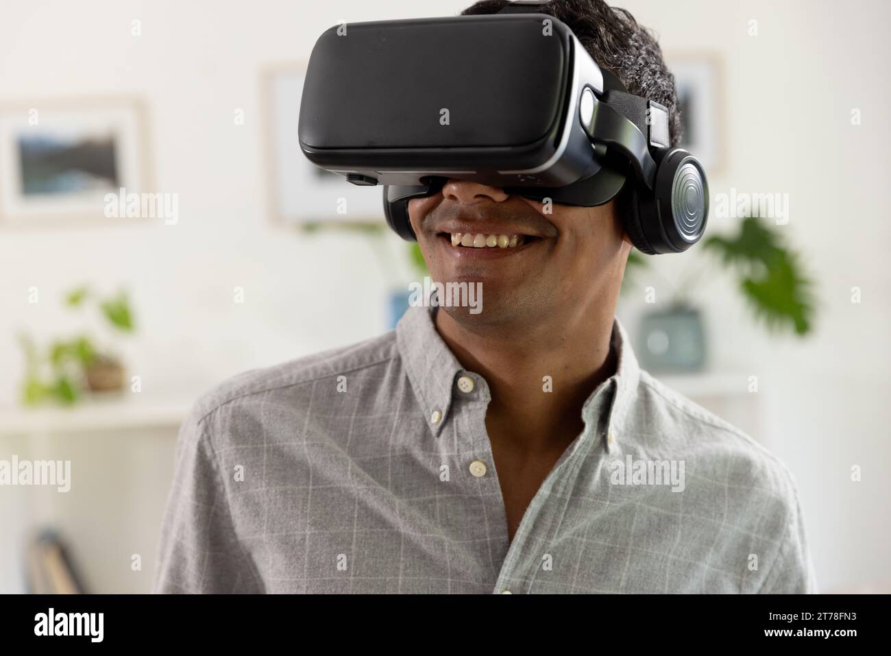 Happy biracial man using vr headset at home Stock Photo