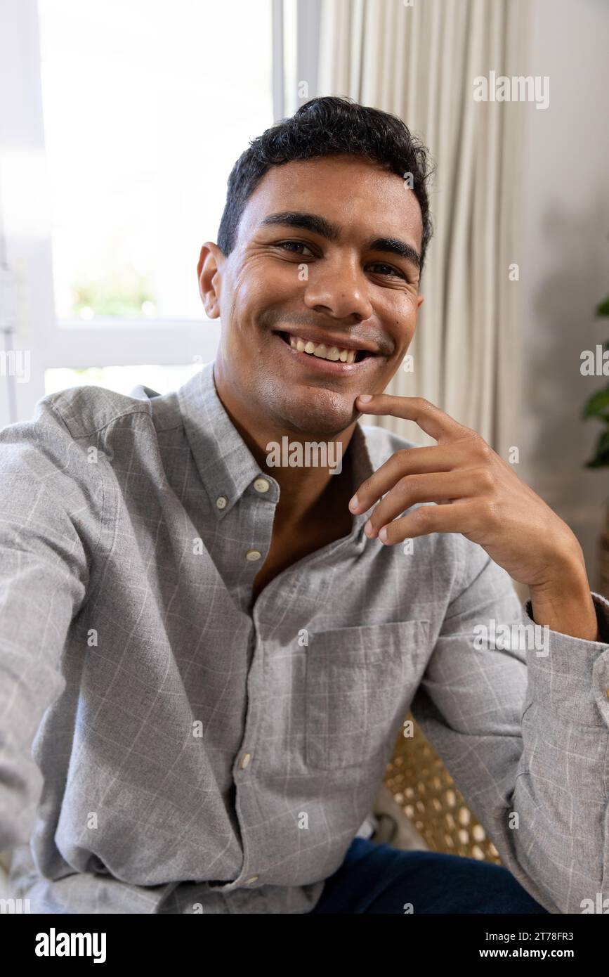 Happy biracial man sitting on armchair having video call at home Stock Photo
