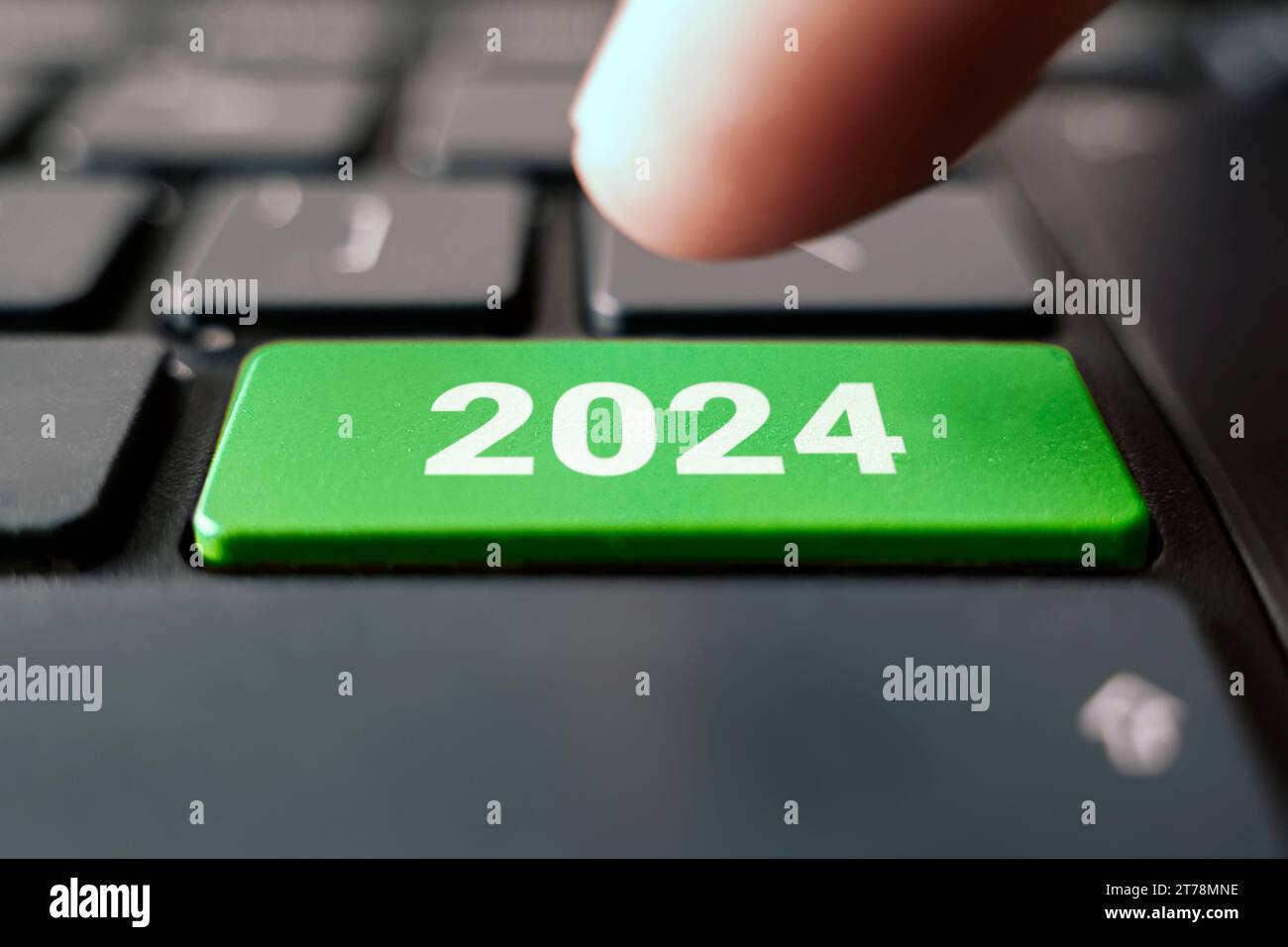 Keyboard with text 2024 year and finger pushing the enter button. Color button on the gray silver keyboard of modern ultrabook. caption on the button. Stock Photo