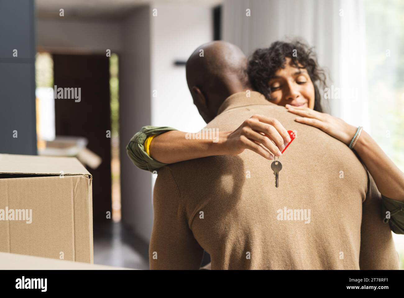 Happy diverse couple embracing and holding house key inside new home ...