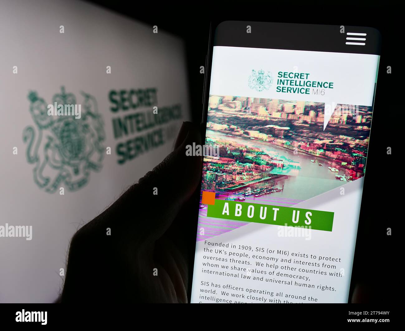 Person holding smartphone with website of British agency Secret Intelligence Service (SIS, MI6) with seal. Focus on center of phone display. Stock Photo