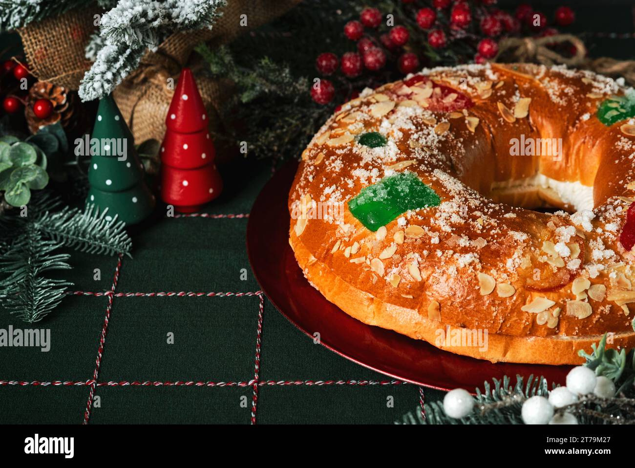 Roscon de reyes with cream on a red plate and christmas ornaments on a christmas tablecloth. Kings day concept spanish three kings cake.Typical spanis Stock Photo