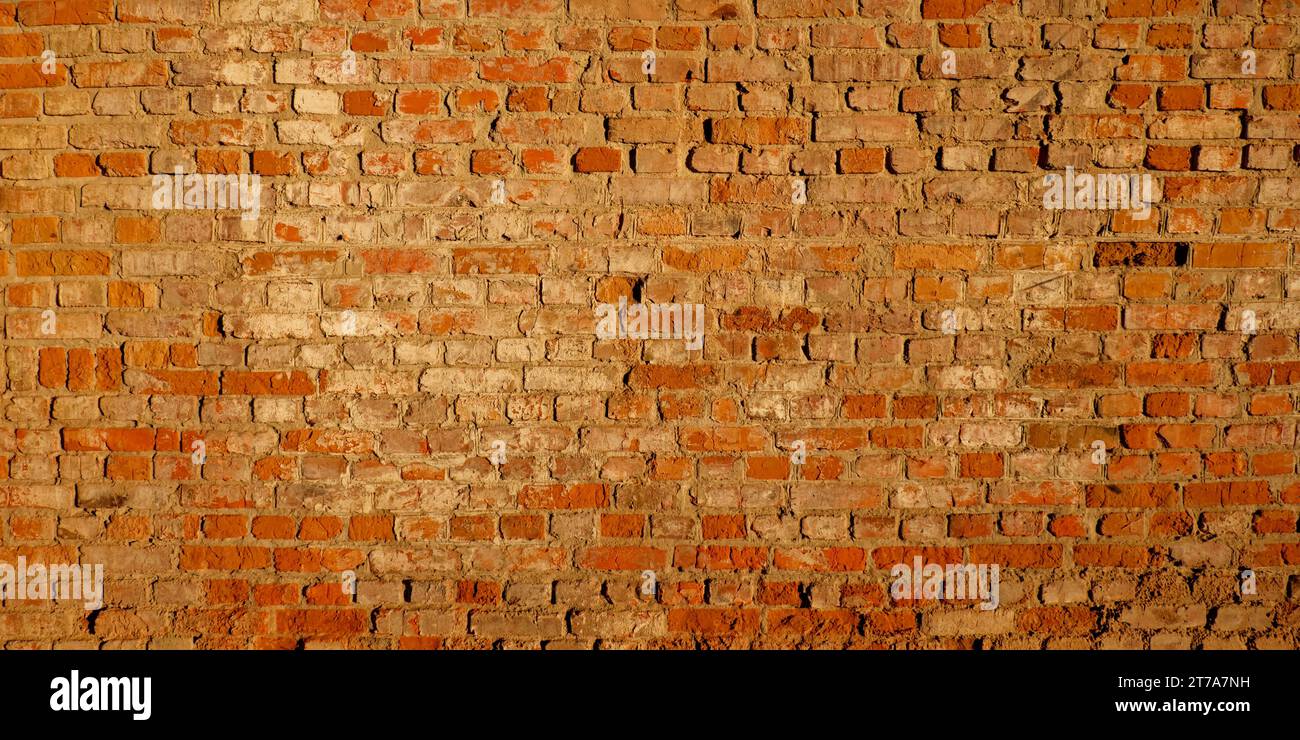 An orange brick wall with gray mortar, showing signs of age. Stock Photo