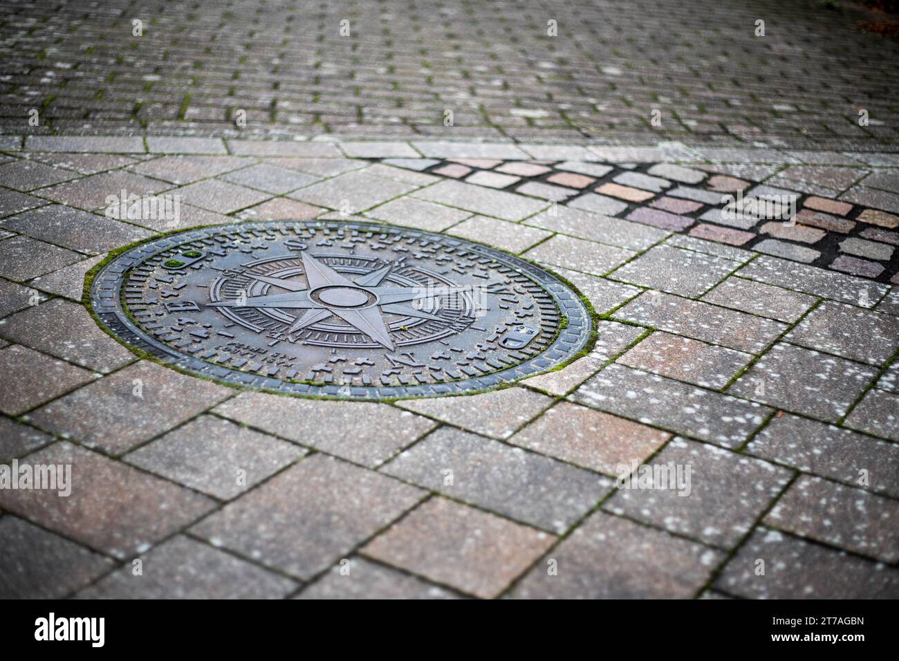 Gullideckel mit Windrose auf einer gepflasterten Straße in der Stadt Stock Photo