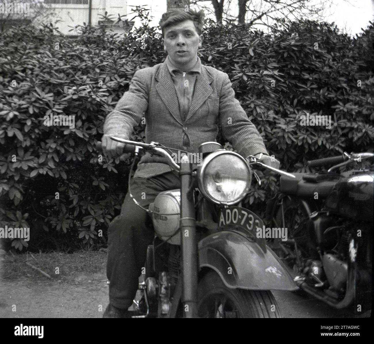 1950s, a young man, early 20s in age, sitting on a Royal Enfield motorcycle of the era, Oldham, Manchester, England, UK. British made Royal Enfield motorcycles were made in Redditch, Worcestershire, by the Enfield Cycle Company, with the first one built dating back to 1901. Stock Photo