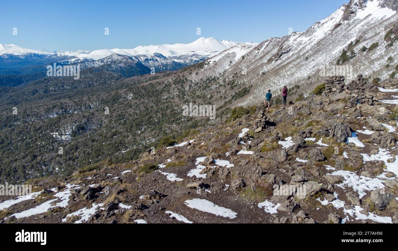 A group of people trekking up a rugged mountainside, with snow-capped peaks in the distance Stock Photo