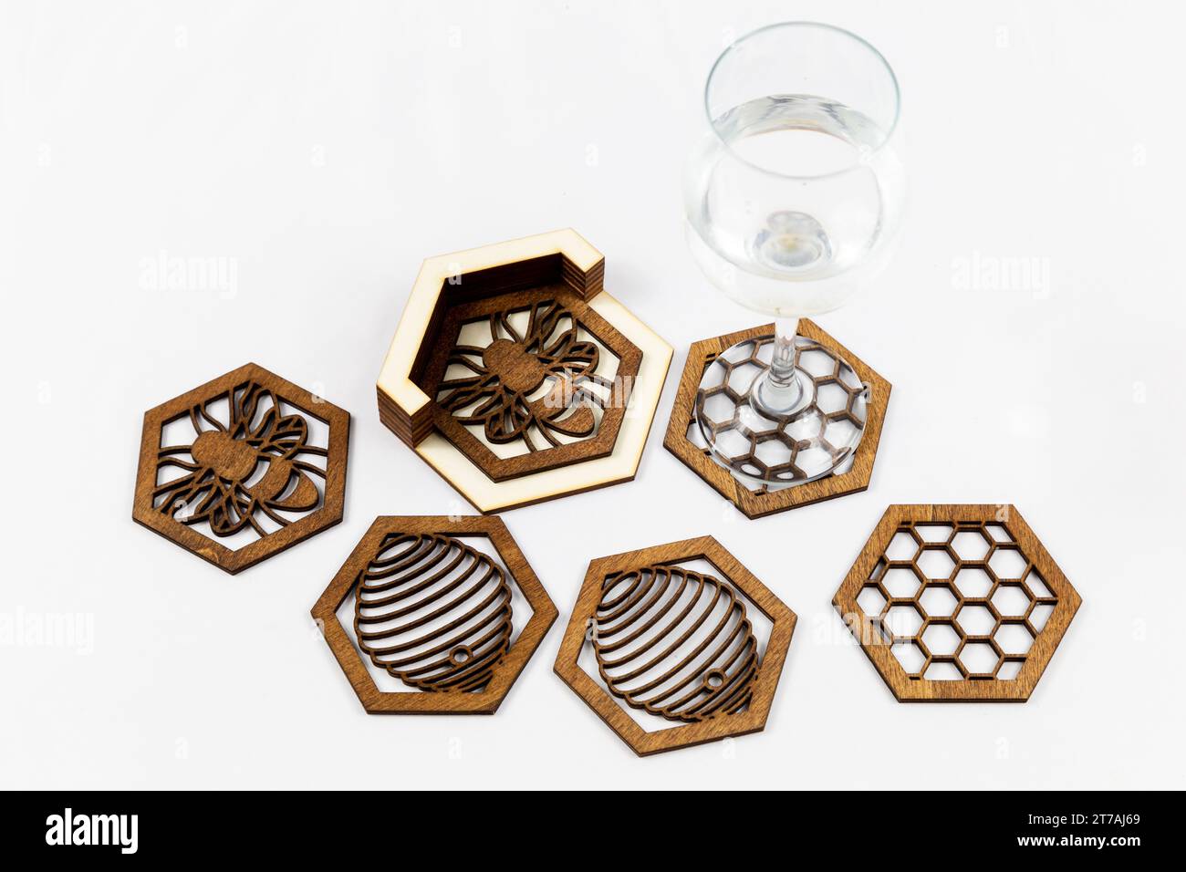 collection of wooden coasters with intricate designs and a wine glass on a white background. The coasters are hexagonal. Stock Photo