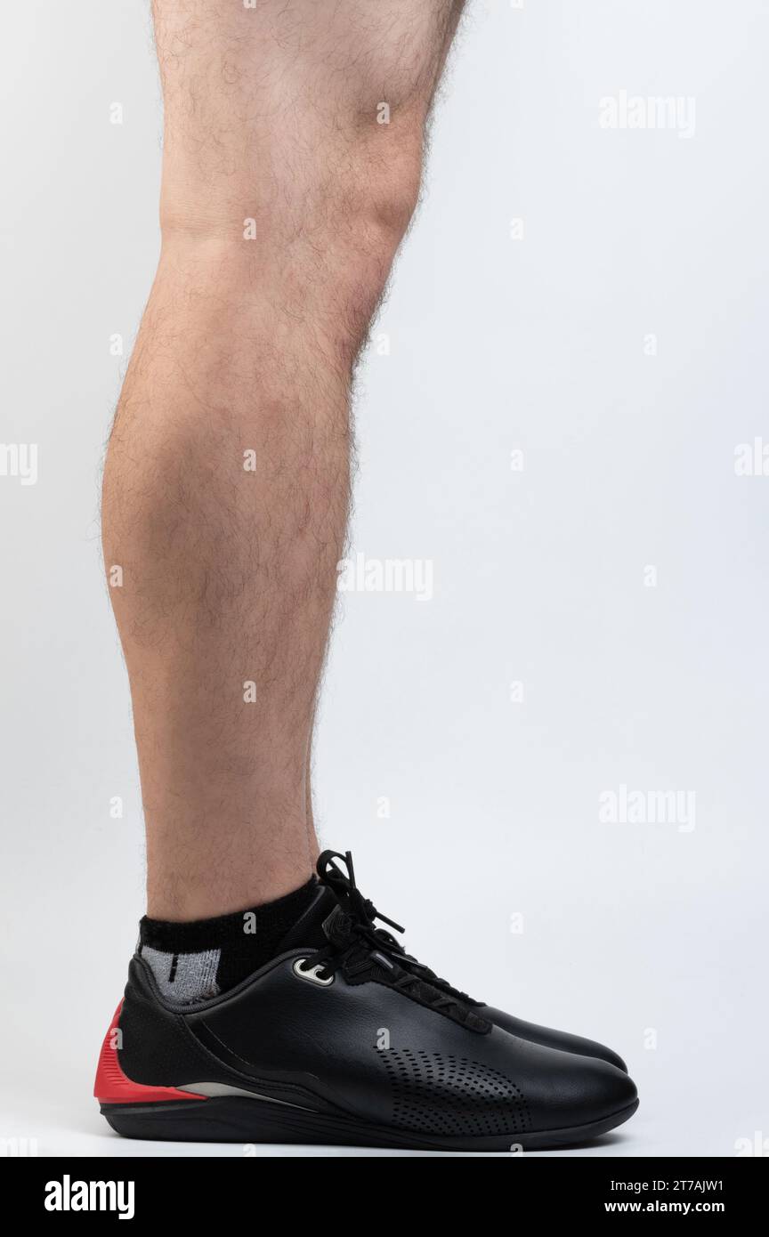 Male leg in black sport shoe side view isolated on studio background Stock Photo