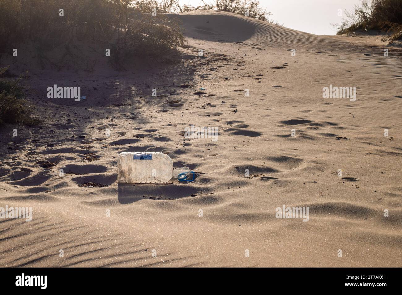 Sand dune with garbage from tourists. A plastic bottle is lying on the sand. Stock Photo