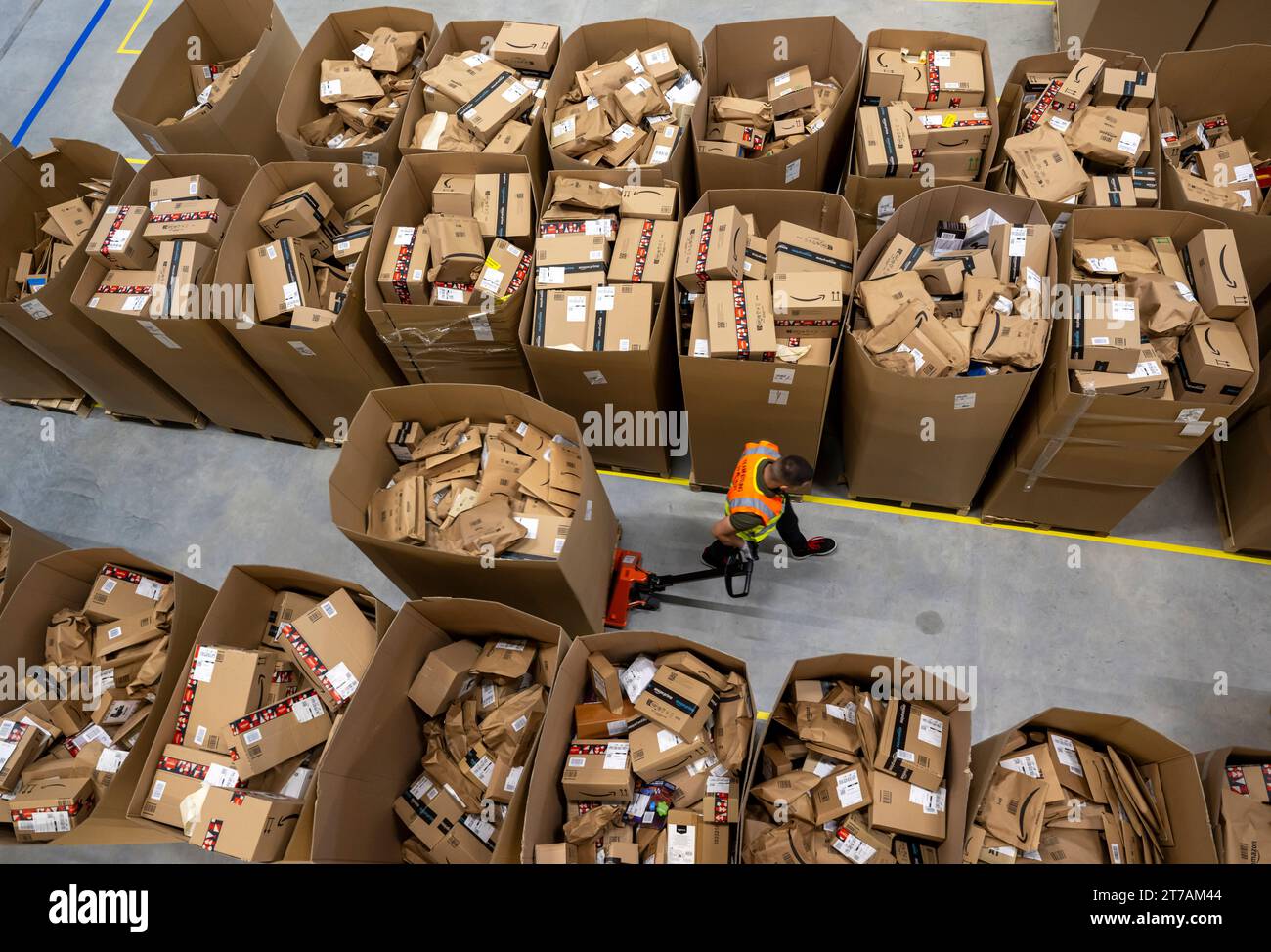 Erding, Germany. 14th Nov, 2023. An Amazon employee drives a forklift through sorted parcels at