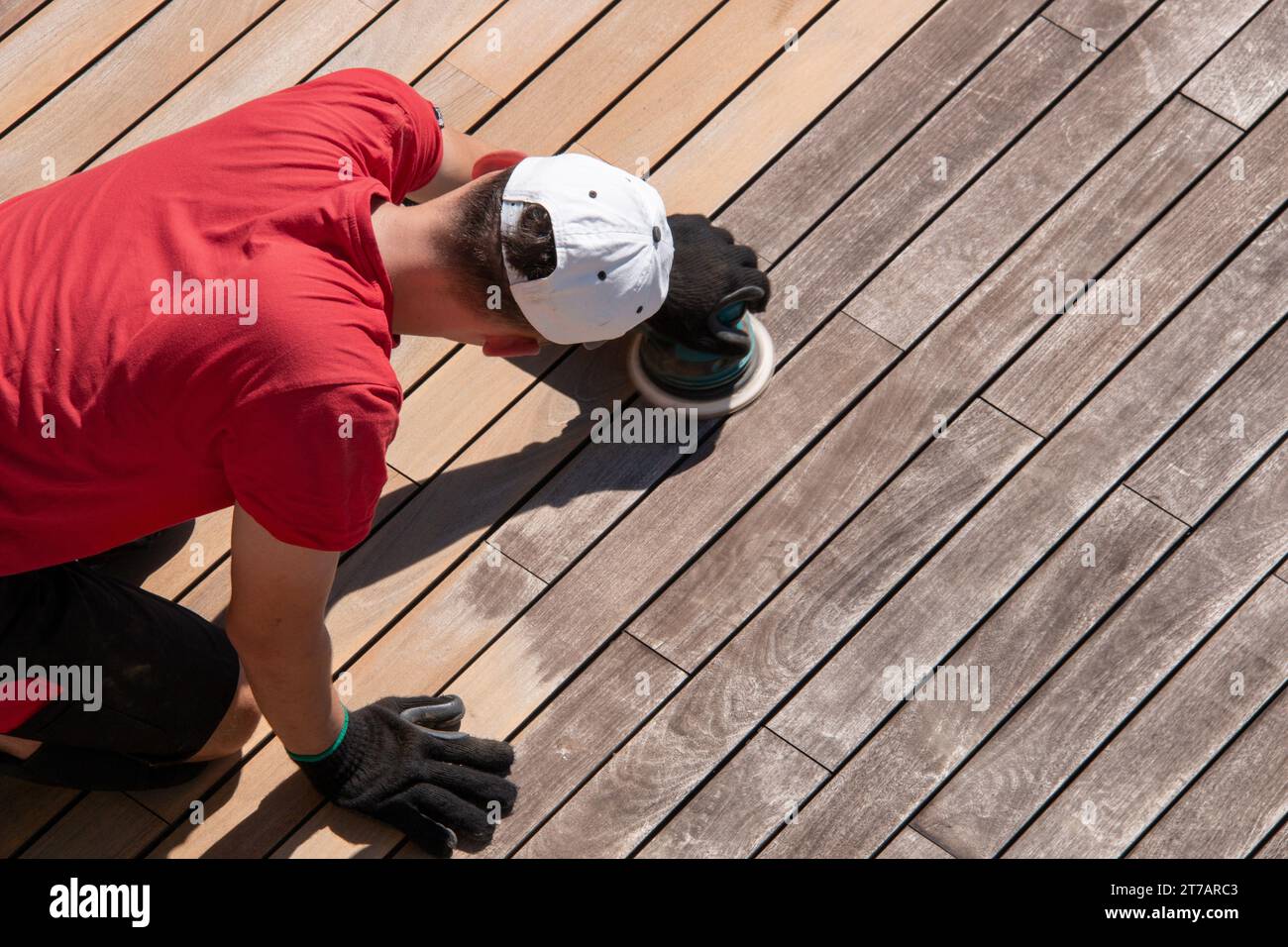 Man sanding weathered grey ipe surface, deck boards before and after