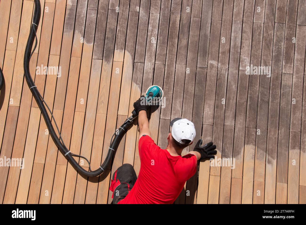 Wood decking maintenance, man sanding and cleaning deck, weathered grey