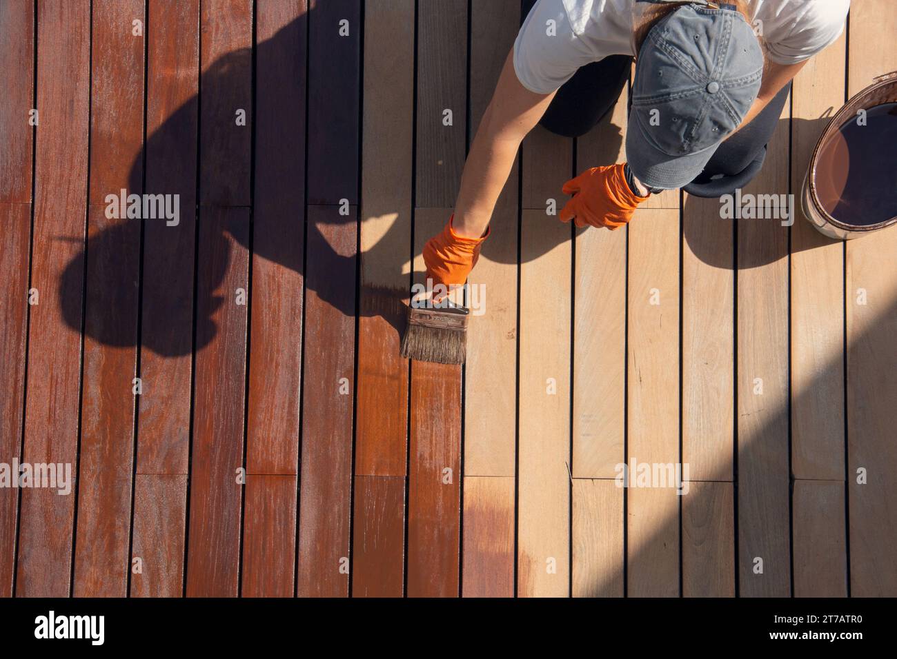 Exterior wood deck sealing and staining, overhead worker applying
