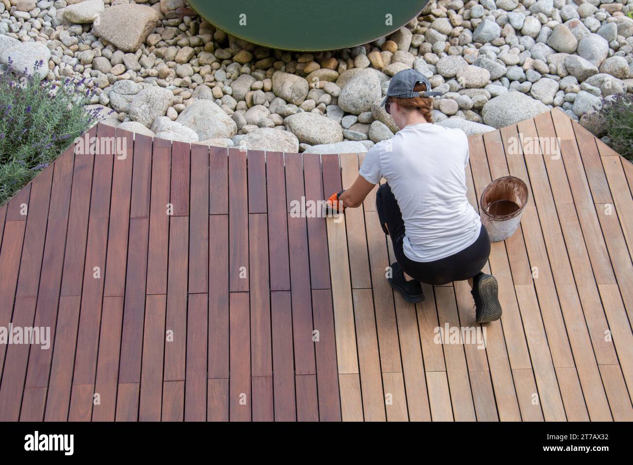 Hardwood deck oil application, overhead woman painting wood boards of