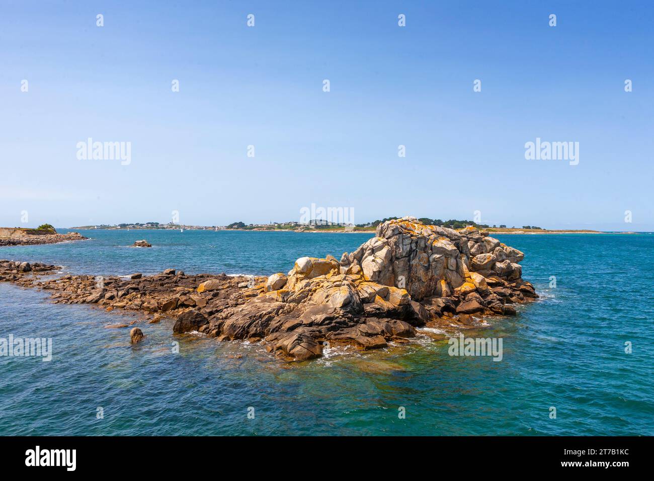 Half-tide rocks off the Old Port of Roscoff, with the Île de Batz in the distance: Finistère, Brittany, France Stock Photo