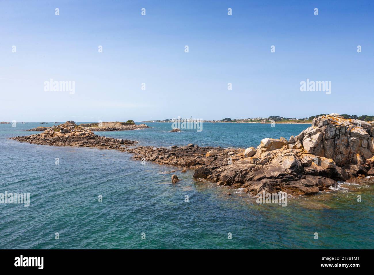 Half-tide rocks off the Old Port of Roscoff, with the Île de Batz in the distance: Finistère, Brittany, France Stock Photo
