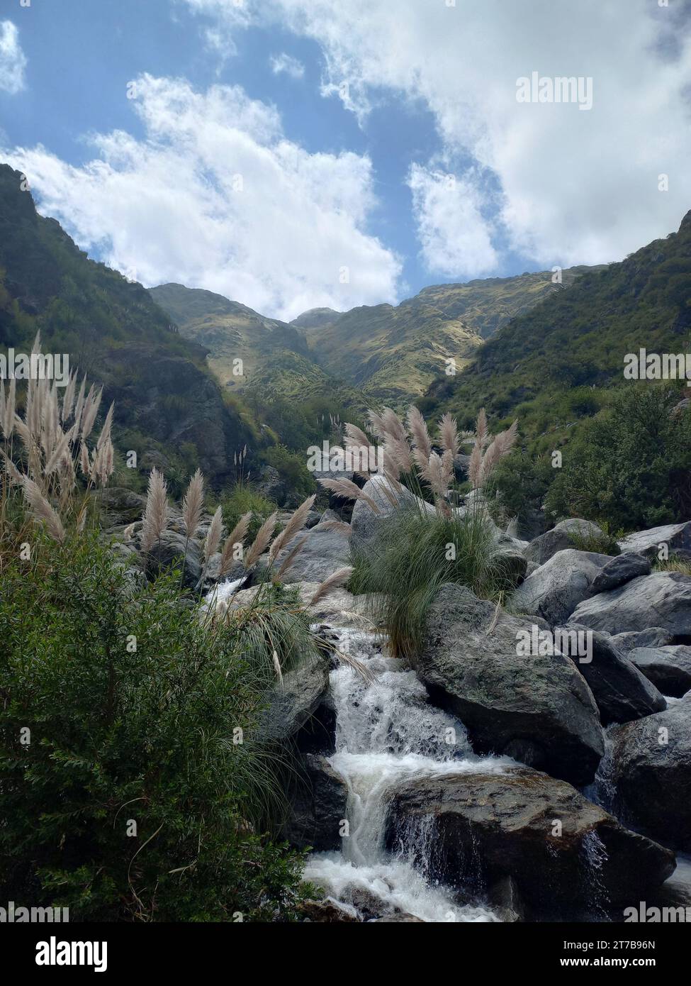 A majestic waterfall cascades down a rocky valley, surrounded by lush ...