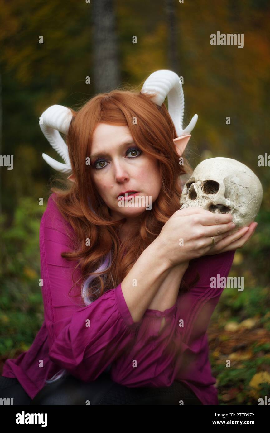 A captivating portrait of a female Tiefling from Dungeons & Dragons, holding a skull with both hands. The subject gazes directly into the camera, expr Stock Photo
