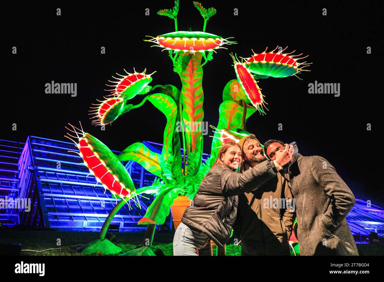 London, UK. 14th Nov, 2023. Kew models take selfies with the vibrant 'Snapper' installation. This John Lewis installation is a replica of the much loved Snapper, a venus fly trap and wannabe Christmas Tree who is the star of their Christmas ad this year. The popular 'Christmas at Kew' returns to Kew Gardens in West London. The original festive trail through Kew's after-dark landscape is returning for its eleventh year with a host of seasonal favourites alongside several new light installations. Credit: Imageplotter/Alamy Live News Stock Photo