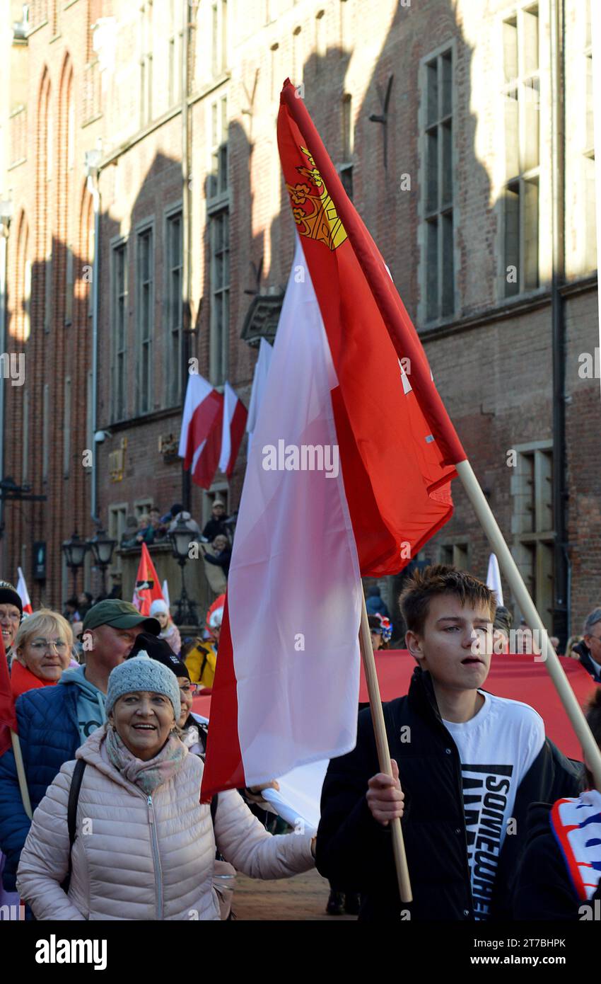 GDANSK, POLAND - 11 NOVEMBER 2023: :Marchers young and old paradewith Polish flags  down Ulica Długa for Polish Independence Day in the Old Town. Stock Photo