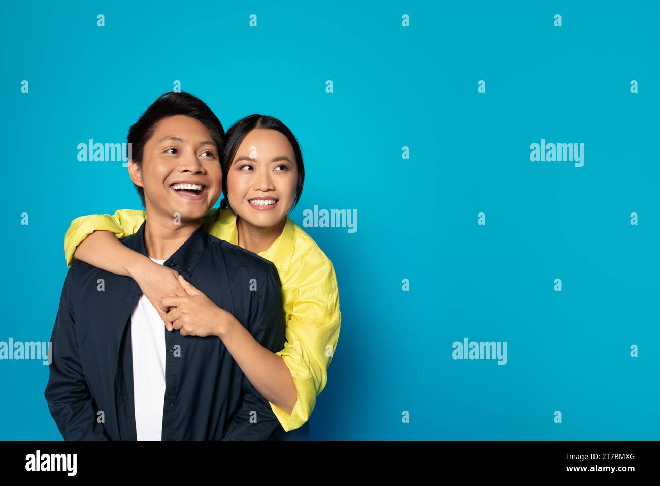 Satisfied millennial korean lady hug guy in casual look at copy space