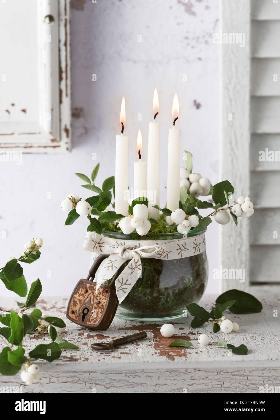 4. Advent. Christmas wreath decoration with white advent candles, snowberry branches in glass jar and vintage lock. Handmade home decoration. Stock Photo