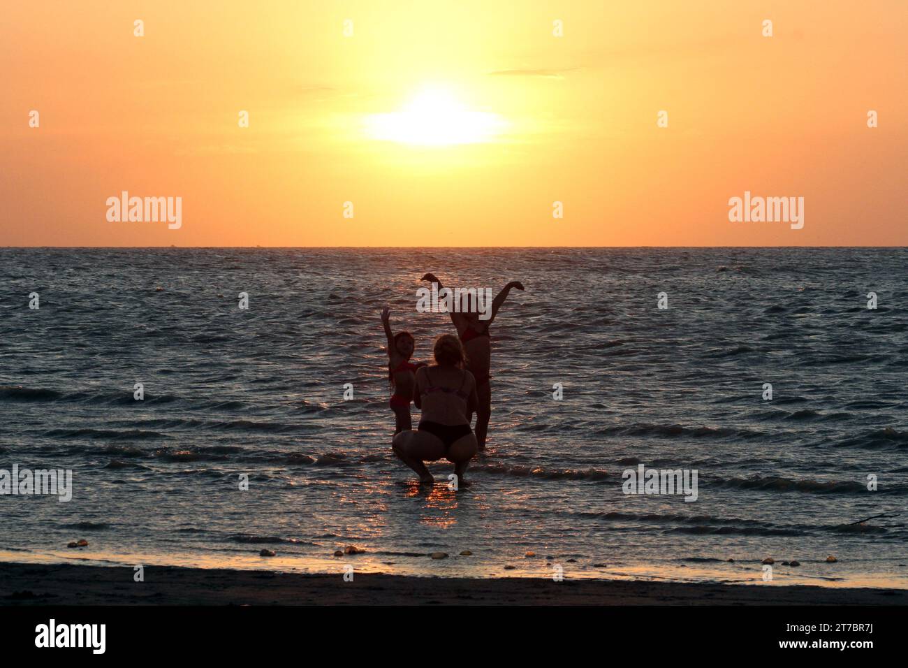 21th, january, 2016; Buenos Aires, Argentina. Mother takes picture of her daughters during sunset on the beach. Stock Photo