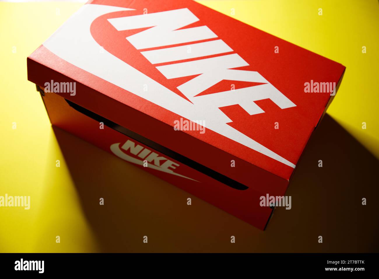 an original bright red vintage style 'Nike' carboard shoe box, with white logo's, against a bright yellow background Stock Photo