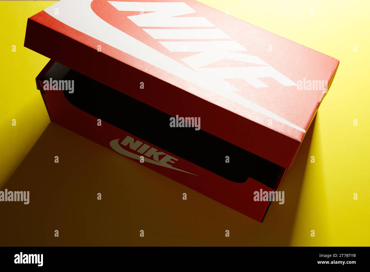 an original bright red vintage style 'Nike' carboard shoe box, with white logo's, against a bright yellow background Stock Photo