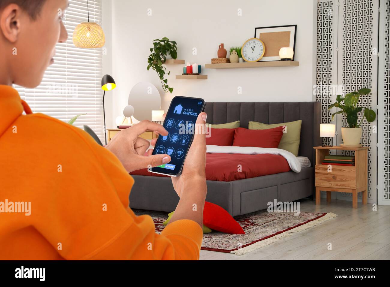 Man using smart home control system via application on mobile phone indoors, closeup Stock Photo