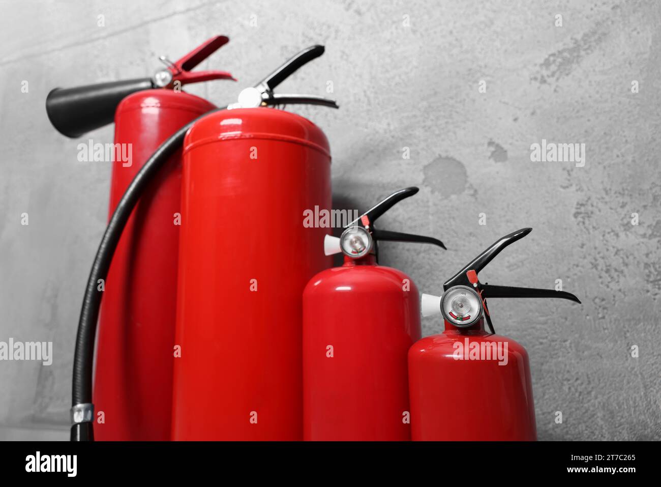 Four red fire extinguishers near grey wall Stock Photo Alamy
