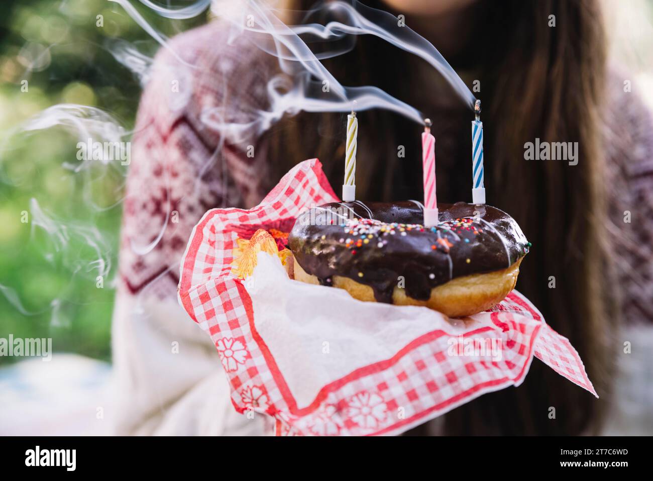 Girl holding chocolate donut with extinguish candles Stock Photo
